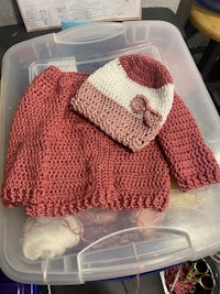 a knitted sweater and hat in a plastic container